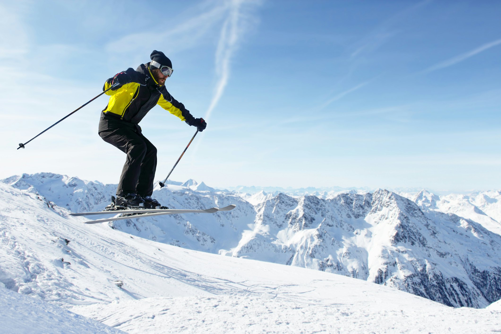 Jumping skier at jump with alpine high mountains