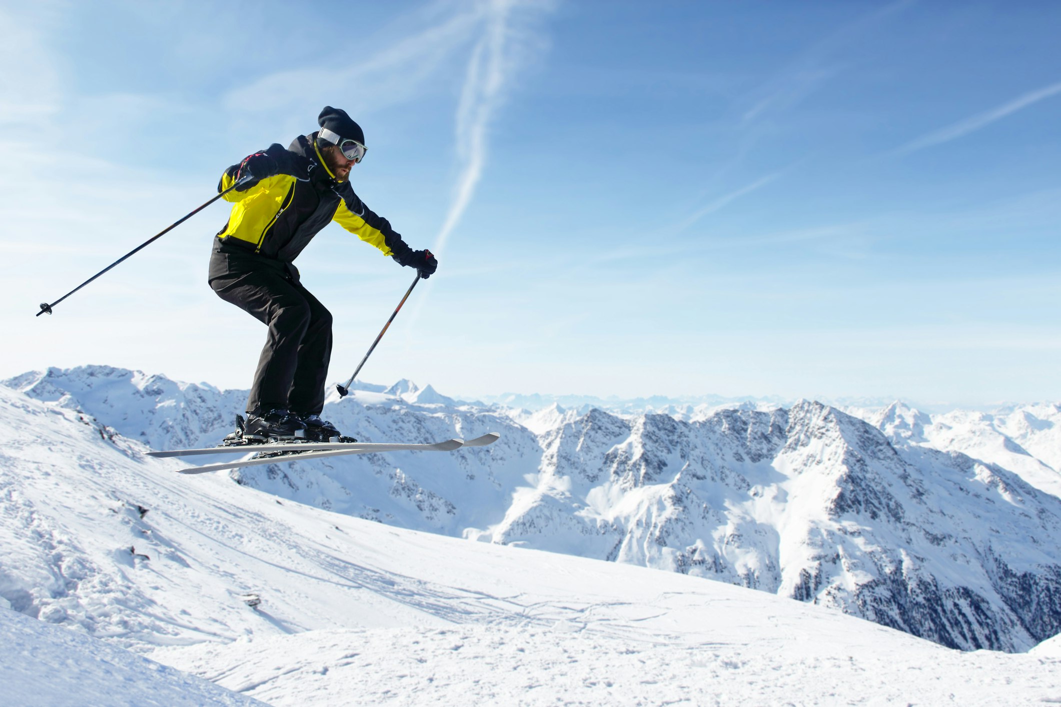 Лыжник прыгает с альпийскими высокими горами позади него