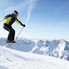 Jumping skier at jump with alpine high mountains