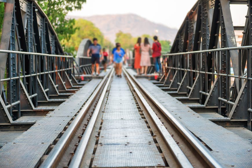 Crowd of people walking by rail track of old railroad bridge on river Kwai. Kanchanaburi, Thailand