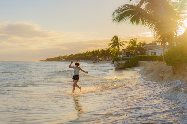 Young woman running happily into the water on a beach in Tulum, Mexico