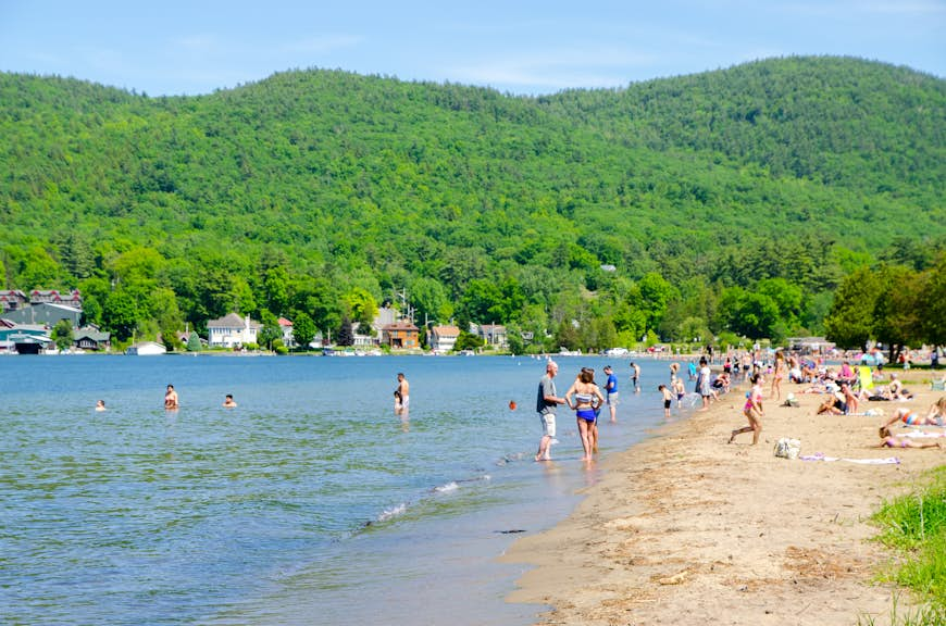 Crowd of swimmers on beach of Lake George (NY) during day of springtime 