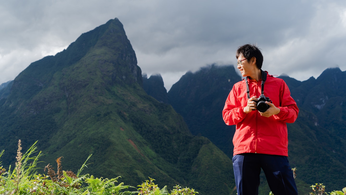 An Asian tourist man watching at Fansipan mountain hills with paddy rice agricultural field valley in summer in travel trip and holidays vacation concept, Sapa, Vietnam.
