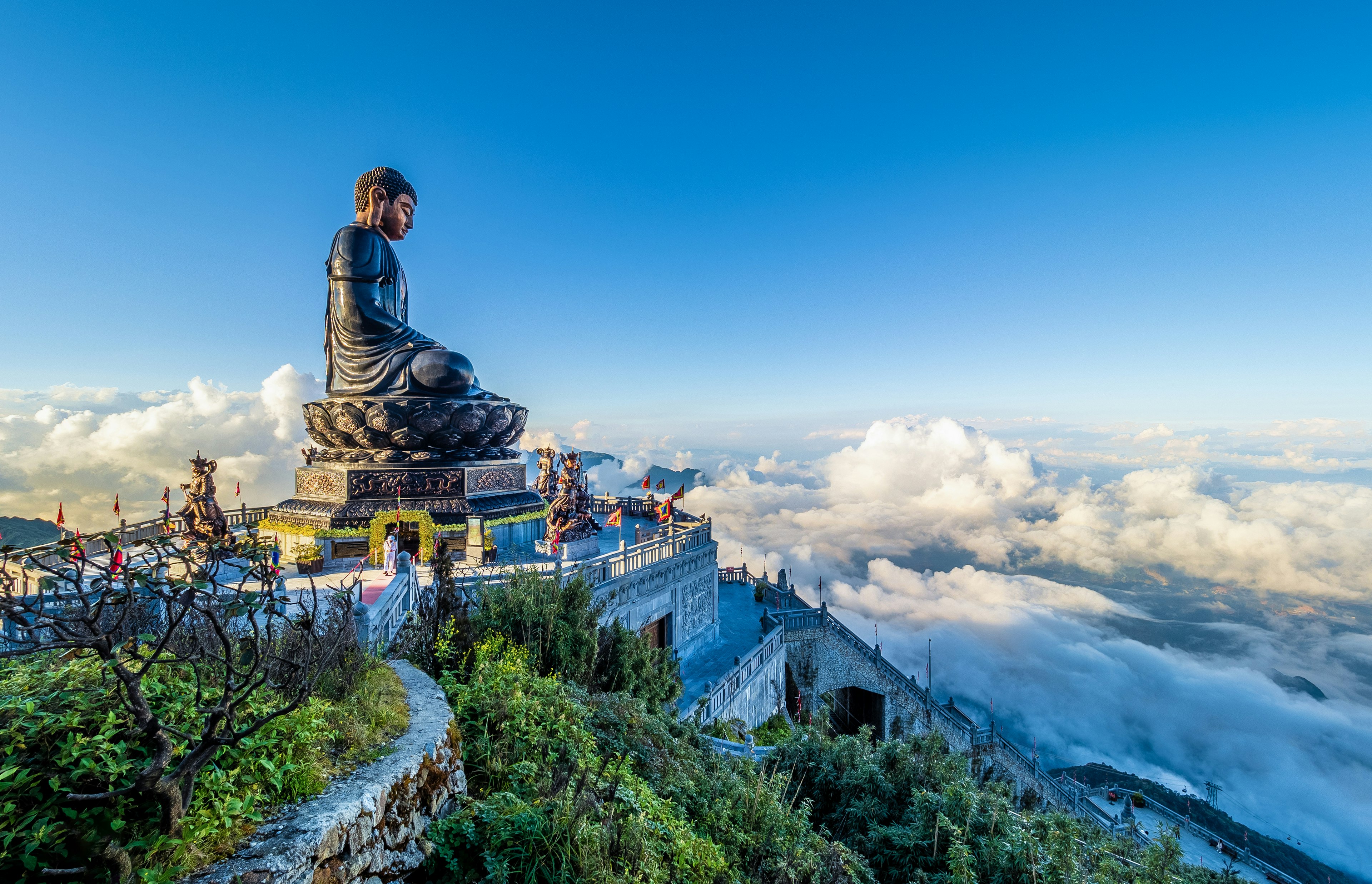 A giant Buddha statue and terrace overlooking clouds and landscapes below from the top of mount Fansipan, Đường District, Lai Chau, Vietnam