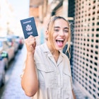Young beautiful blonde caucasian woman smiling happy outdoors on a sunny day showing USA passport
