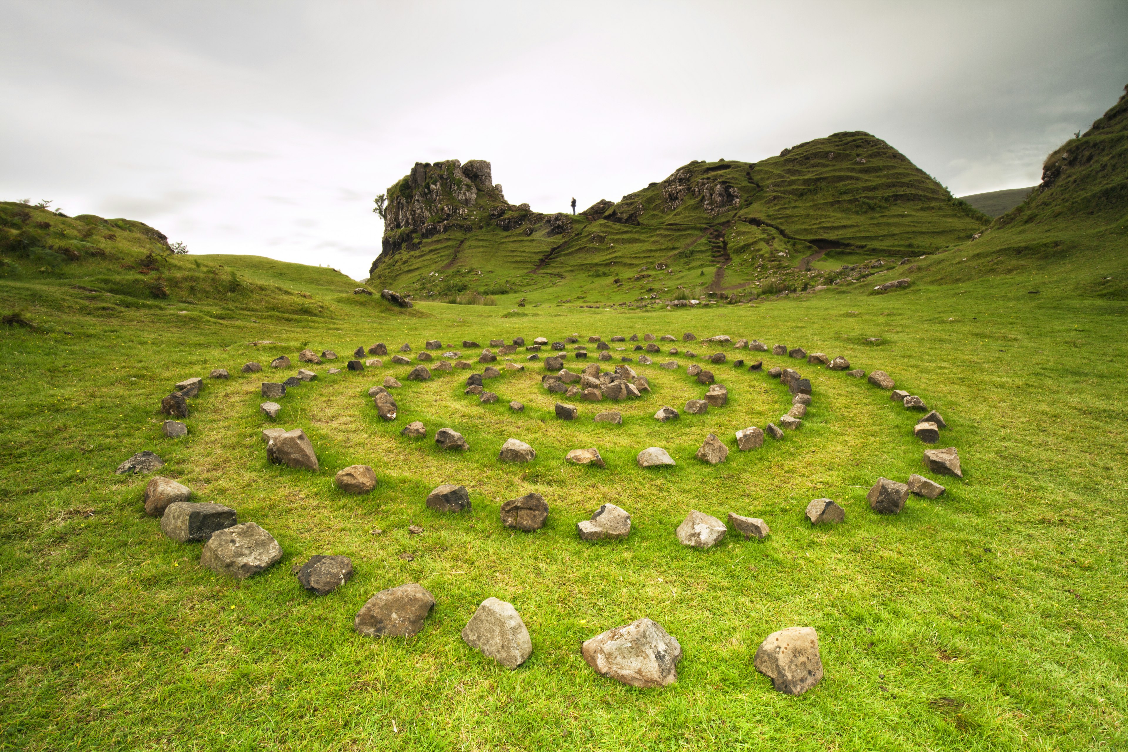 A mystical-looking stone circle its in the lush green grass of Scotland.