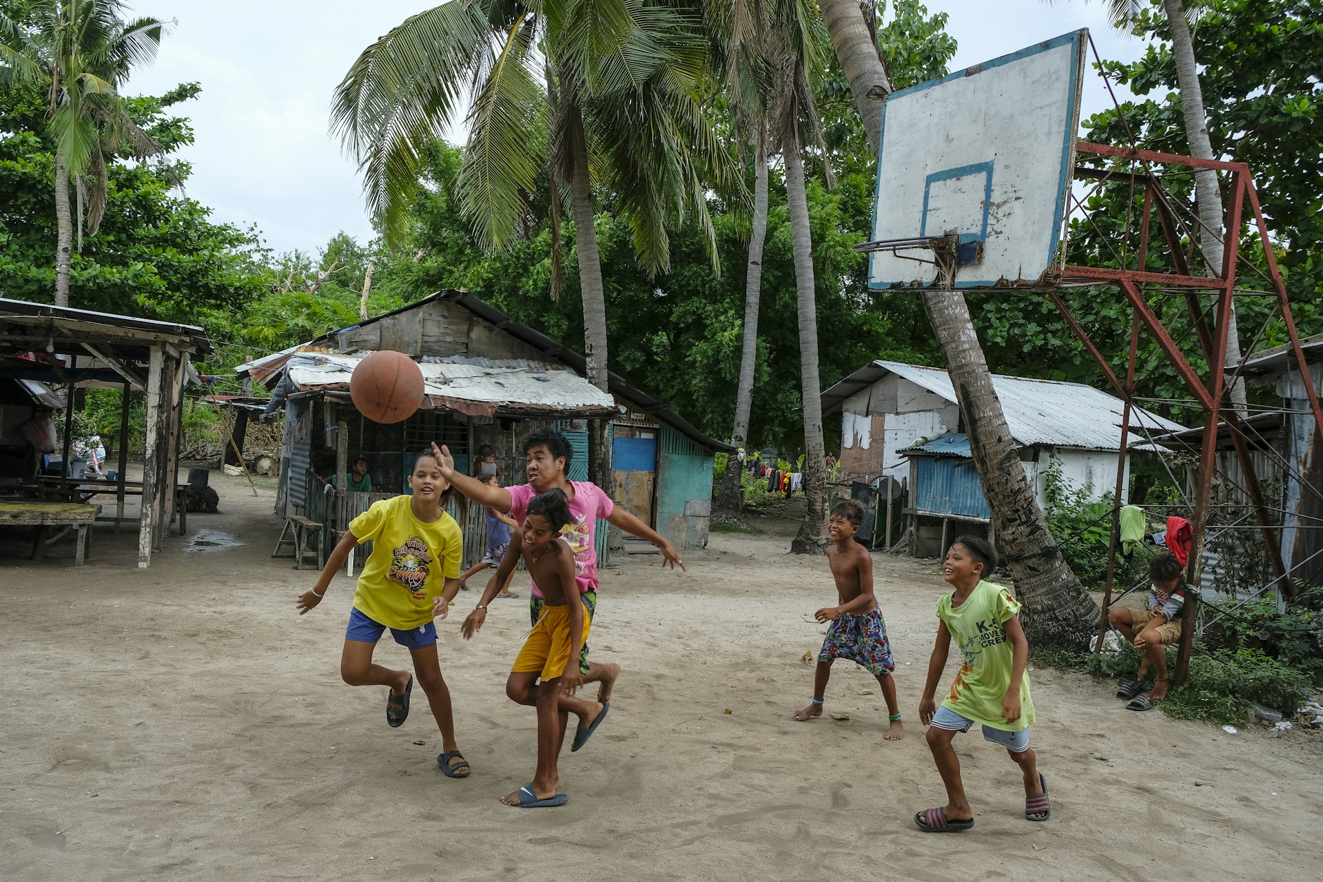 Children playing basketball in front of wooden homes in the Philippines. 
