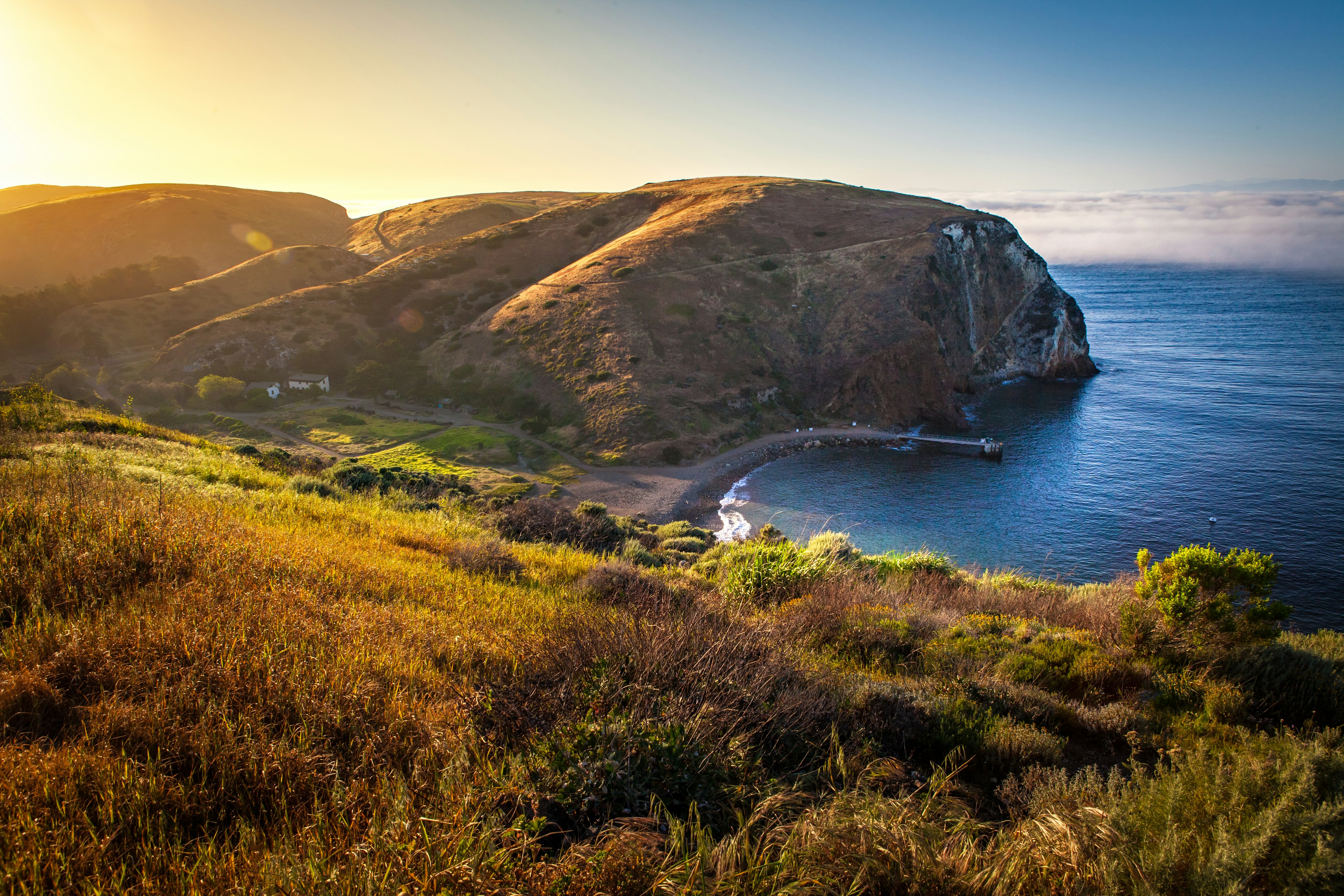 The sun sets over a rocky shore in the summer.