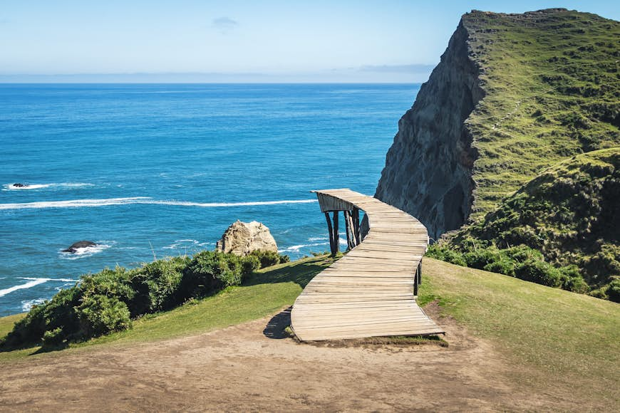 A dock leads out into the water of a cliff in Chile. 