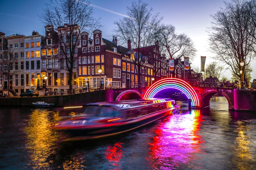 A boat passing through holiday light installations on an Amsterdam canal at night