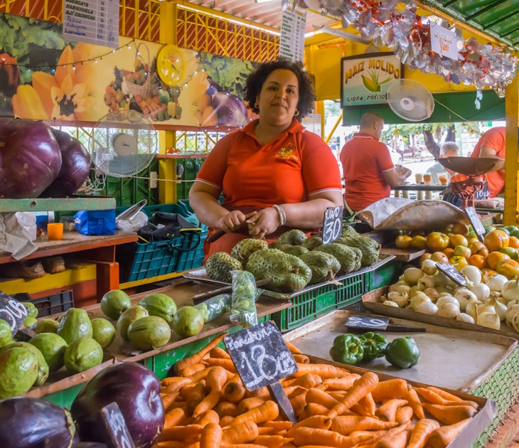 Havana, Cuba - january 15, 2016: Young woman tending inside a fruit and vegetable stand in the agricultural market of a populous neighborhood of the city; Shutterstock ID 1177792096; your: Zach Laks; gl: 65050; netsuite: Online Editorial; full: Discover