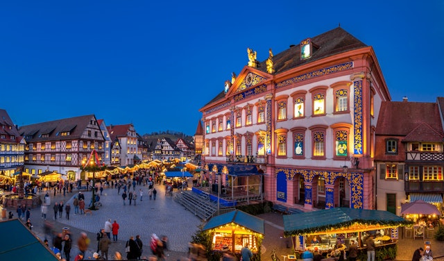 A Christmas market in front of a large building decorated as an Advent calendar