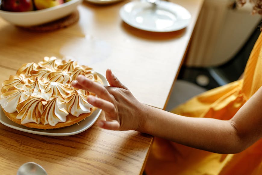 Hand of young girl about to touch a meringue pie
