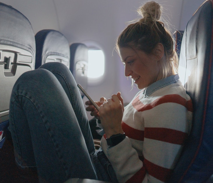 Photo of a young woman checking her smartphone during a flight.