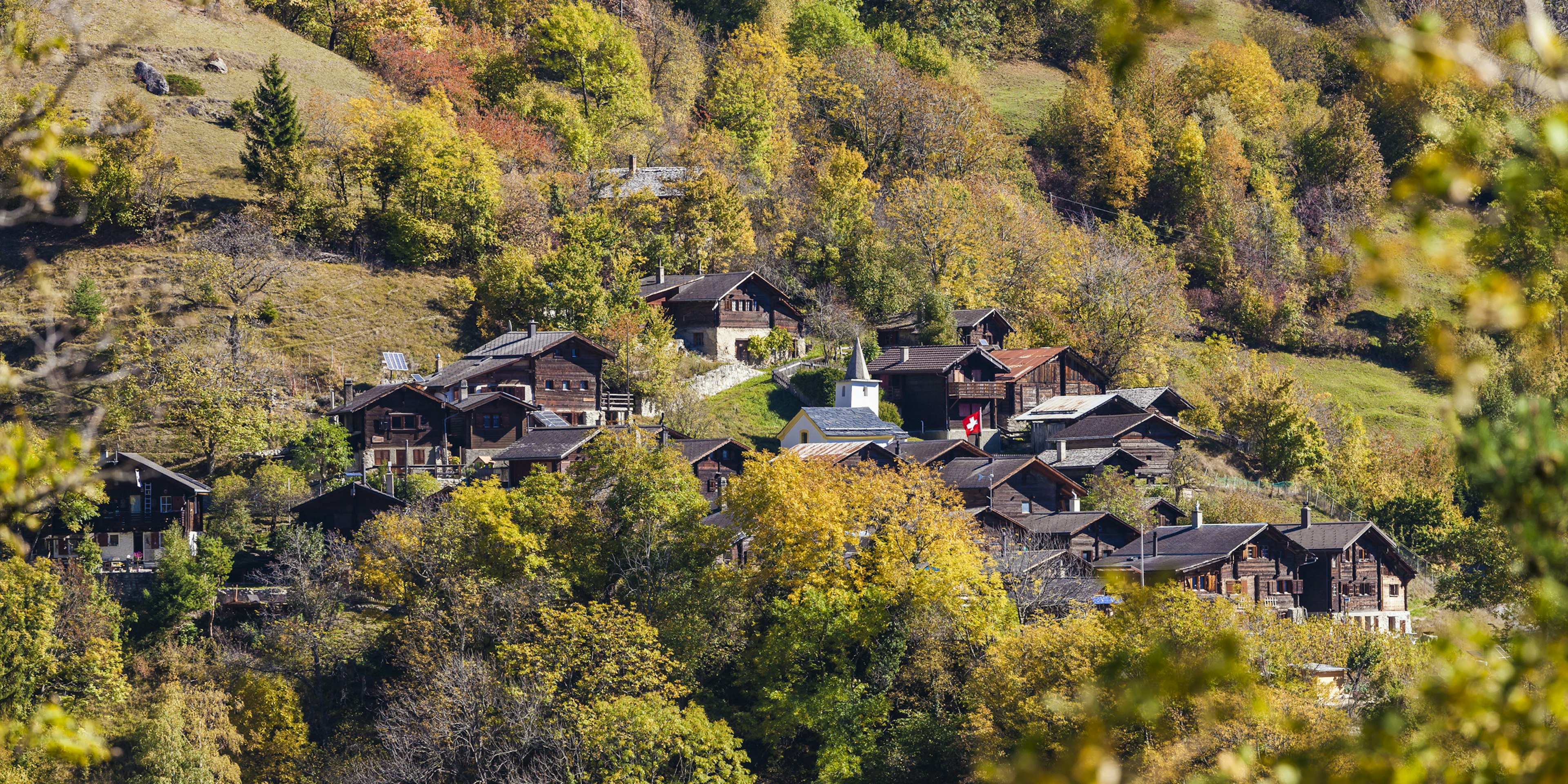 Wooden houses sit high in the Swiss mountains.