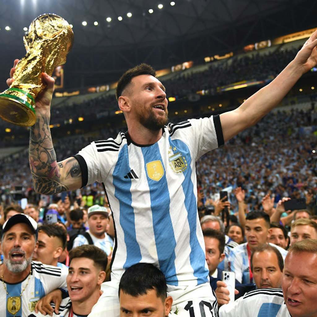 LUSAIL CITY, QATAR - DECEMBER 18: Lionel Messi of Argentina celebrates with the FIFA World Cup Qatar 2022 Winner's Trophy on the shoulders of former teammate Sergio Aguero after the team's victory during the FIFA World Cup Qatar 2022 Final match between A