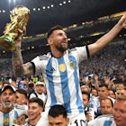 LUSAIL CITY, QATAR - DECEMBER 18: Lionel Messi of Argentina celebrates with the FIFA World Cup Qatar 2022 Winner's Trophy on the shoulders of former teammate Sergio Aguero after the team's victory during the FIFA World Cup Qatar 2022 Final match between A