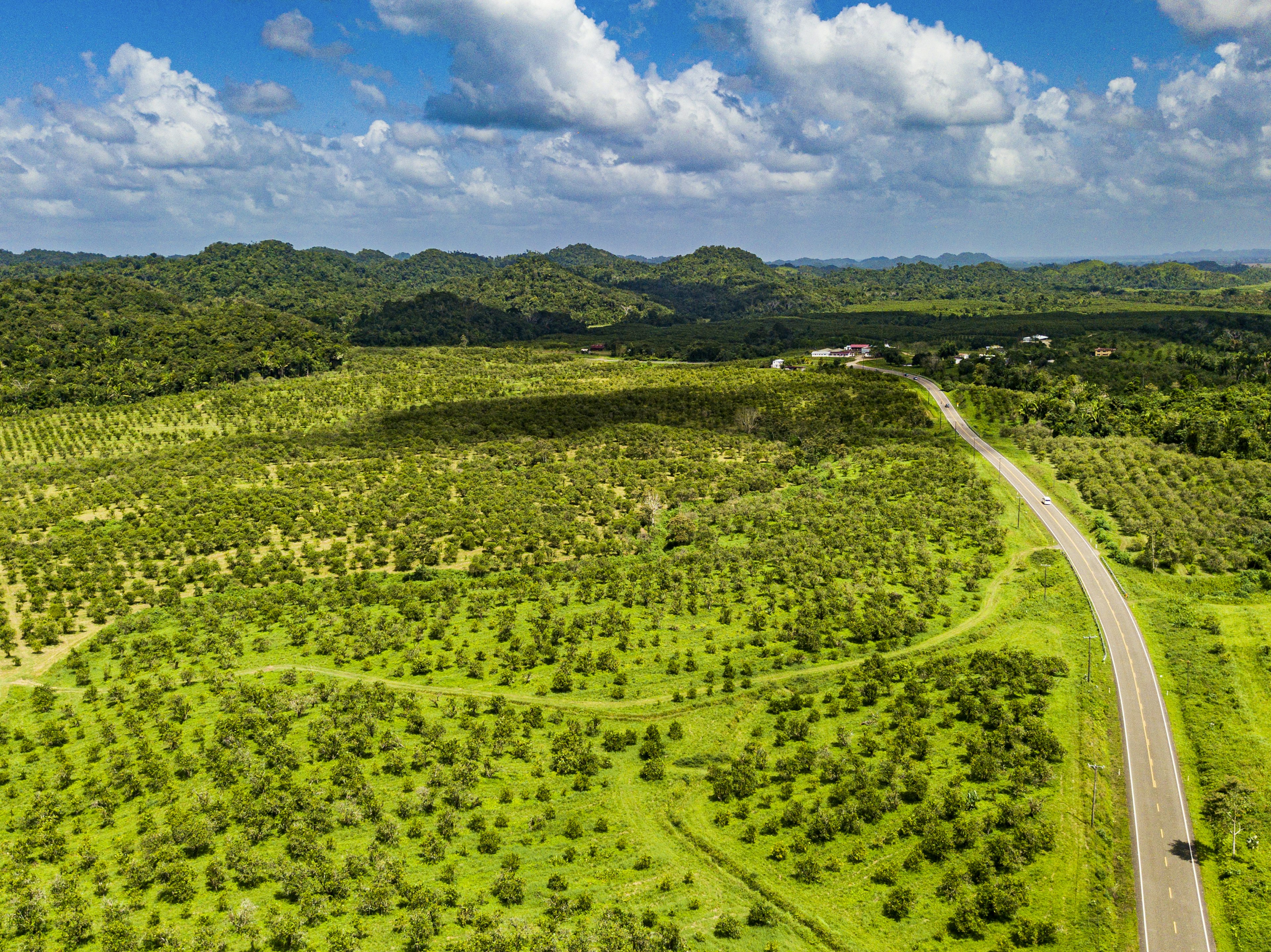 A highway snakes through a gently rolling landscape of green hills and fields