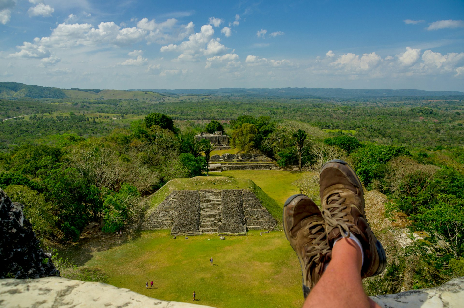 A pair of feet in hiking boots rest at a viewpoint above an ancient city in the jungle