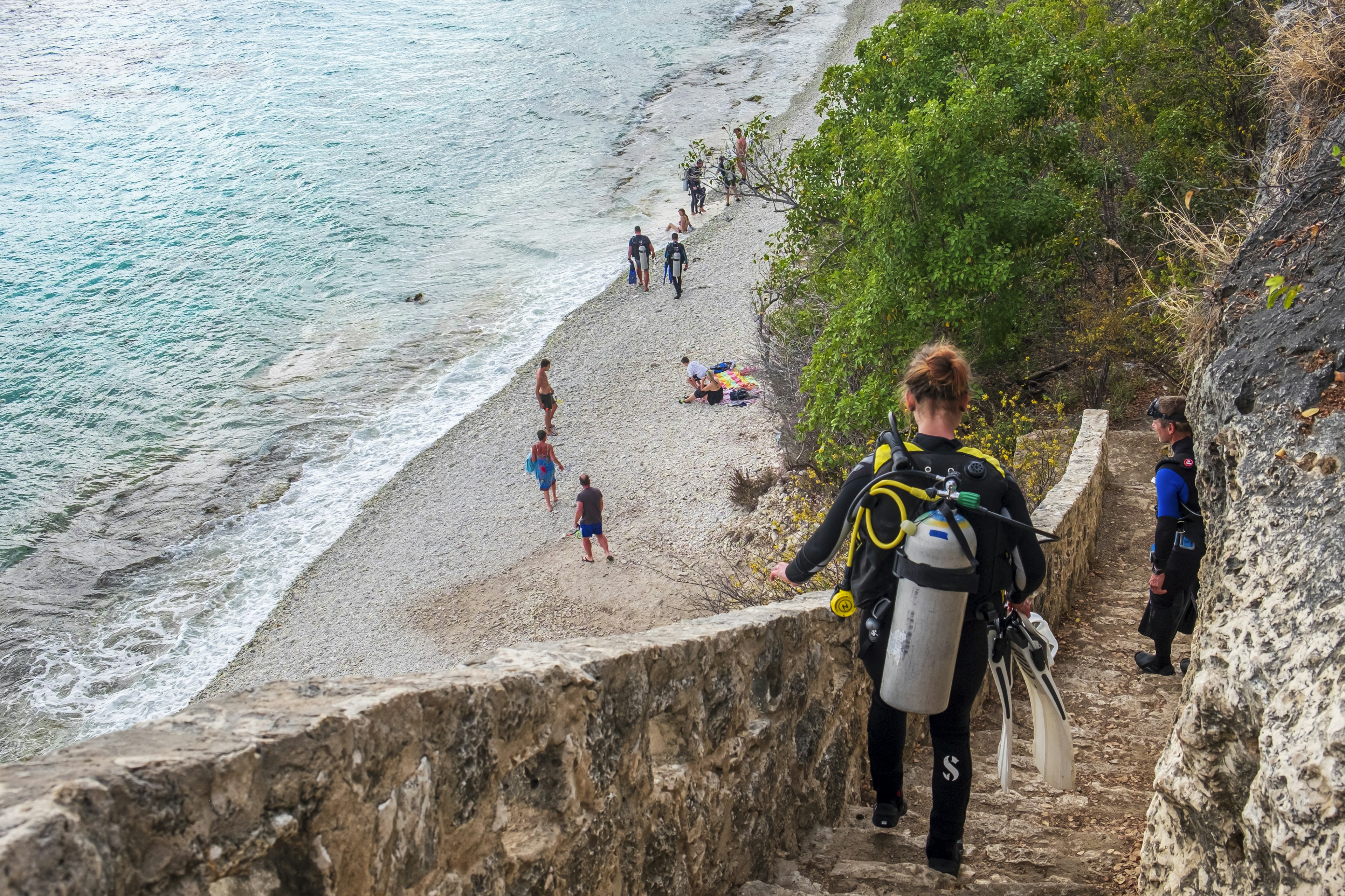 Scuba divers going down the stairs to the 1000 Steps dive site and beach, one of the great spots for diving and snorkeling in Bonaire, in the Caribbean Netherlands