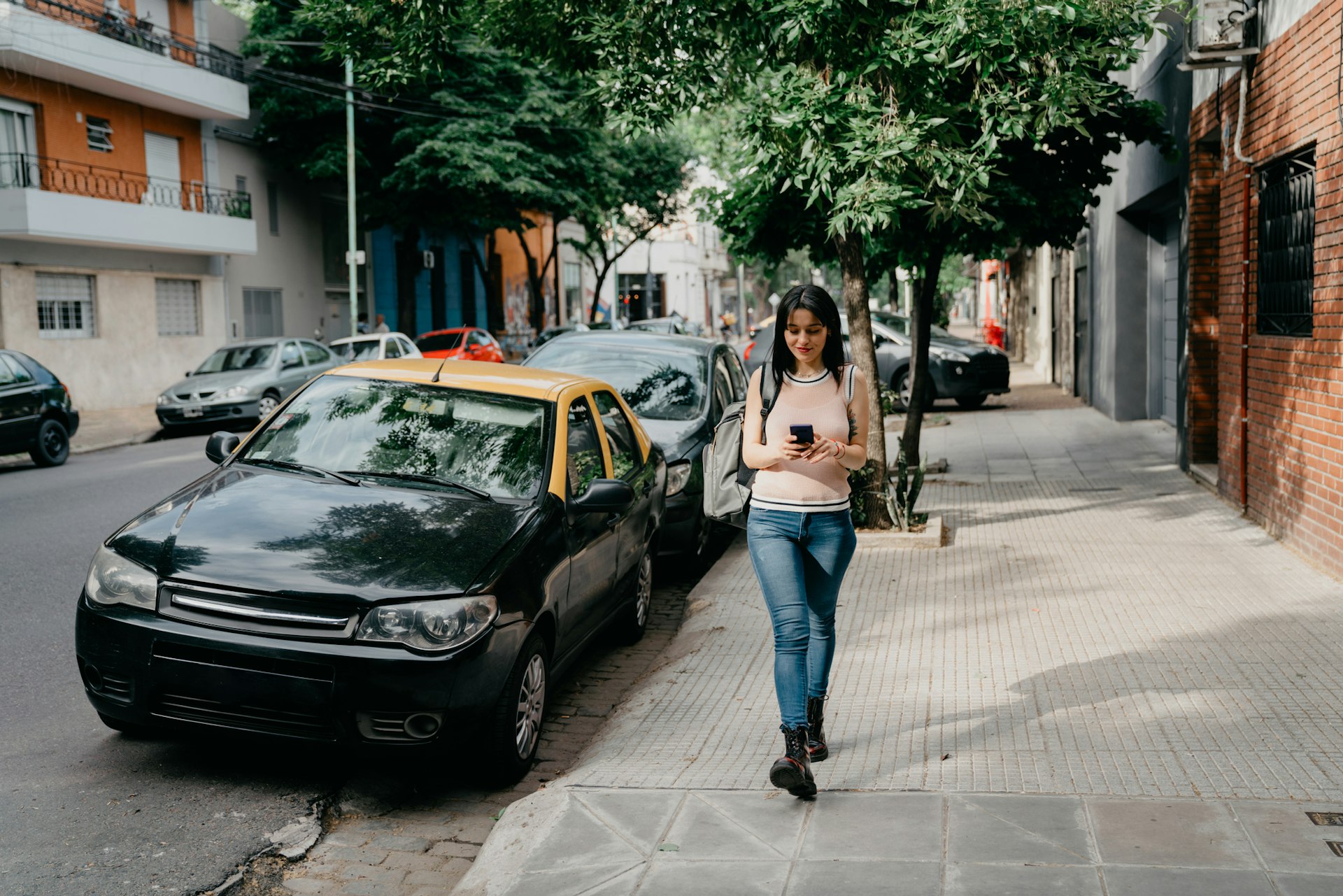 Young adult woman using a mobile phone while she's walking on the street. 