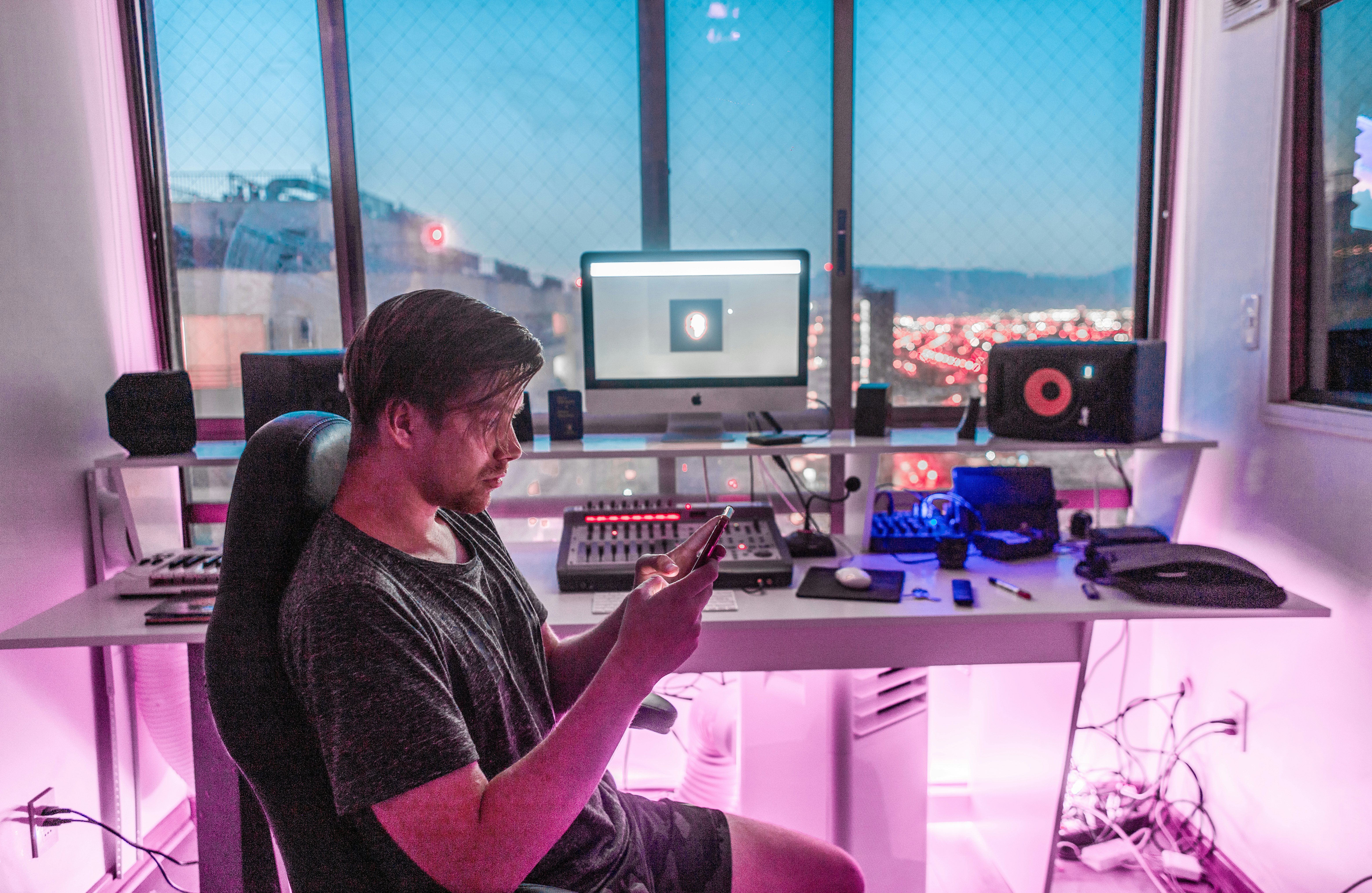 A man works at his home office, which has a purple glow, overlooking the lights of Santiago, Chile