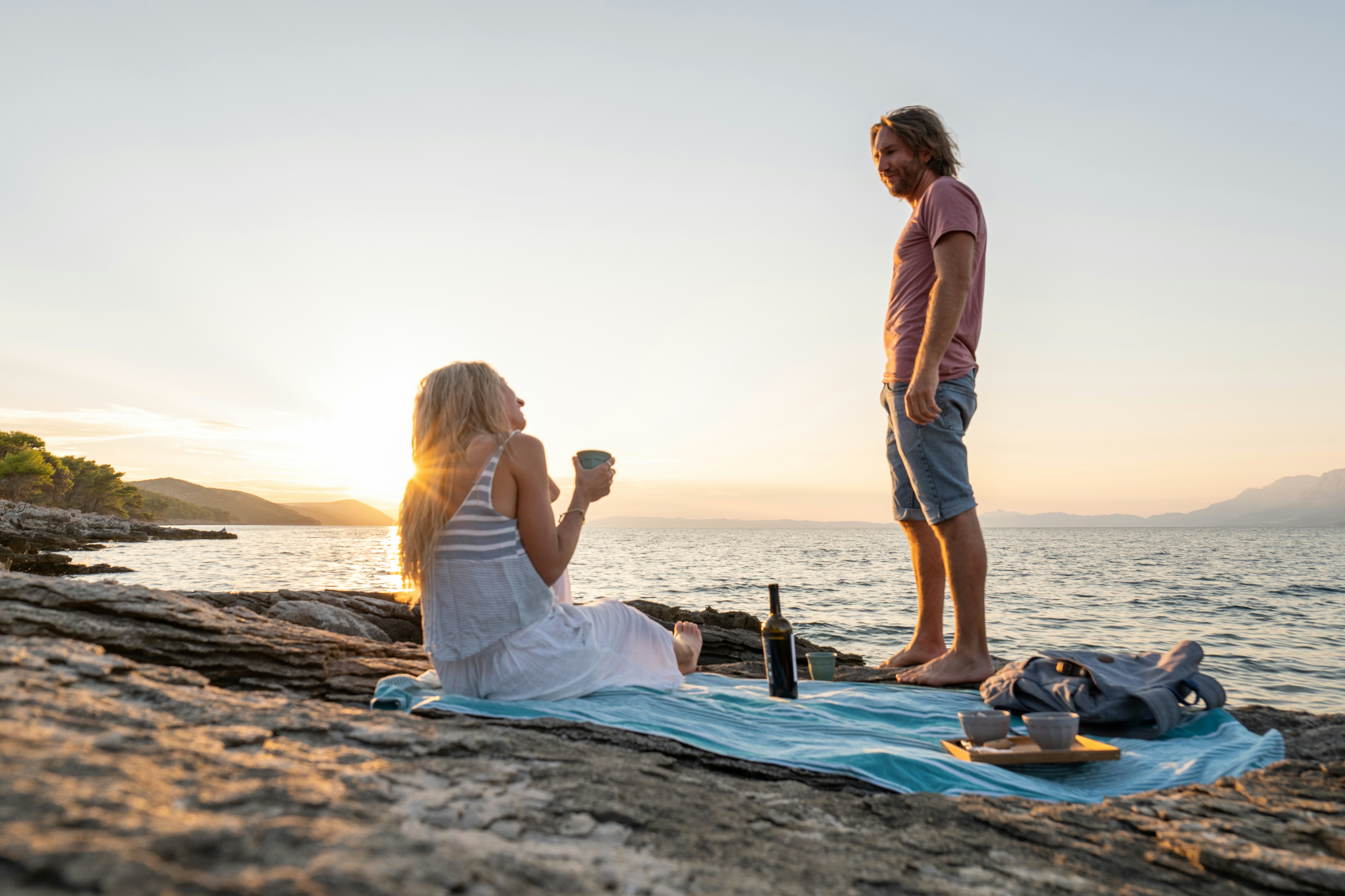 A young couple enjoys drinks by the sea at sunset, Hvar, Croatia