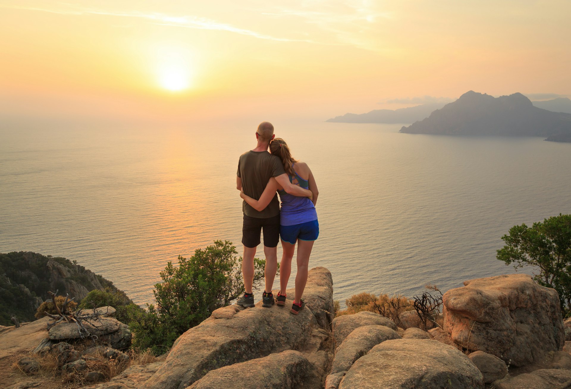 A couple enjoying the sunset over the Golf of Porto at Château Fort, Corsica, France