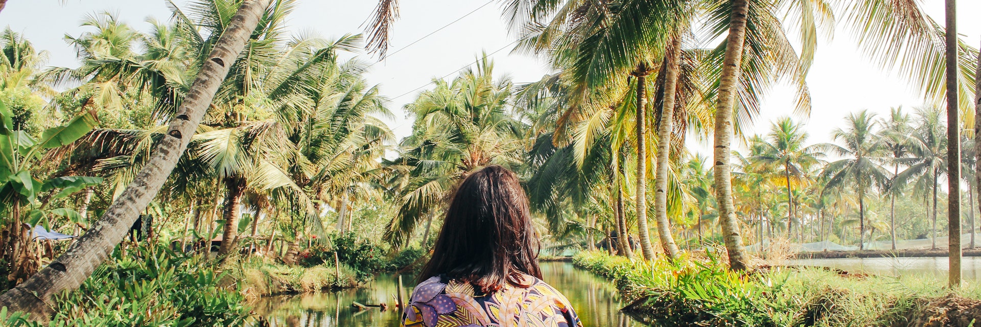 A young woman kayaks through the backwaters of Monroe Island in Kollam District, Kerala, South India.