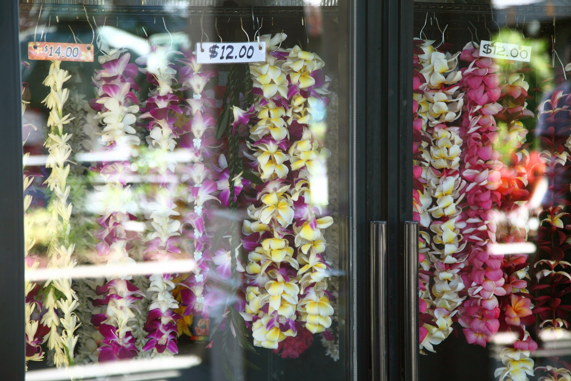 Strands of flowers forming garlands hang in a shop window