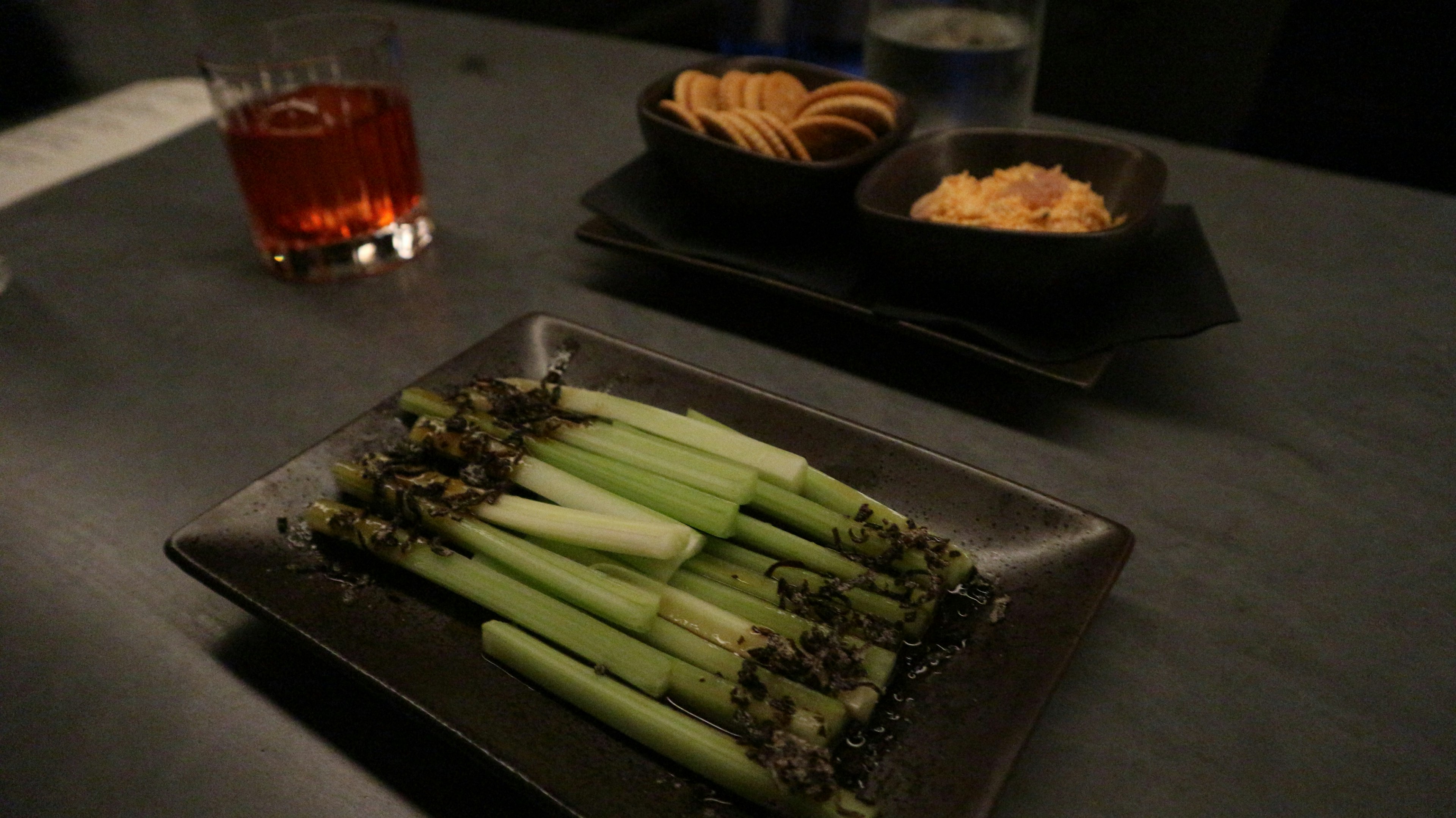 A plate of celery and bar snacks in a dark bar.