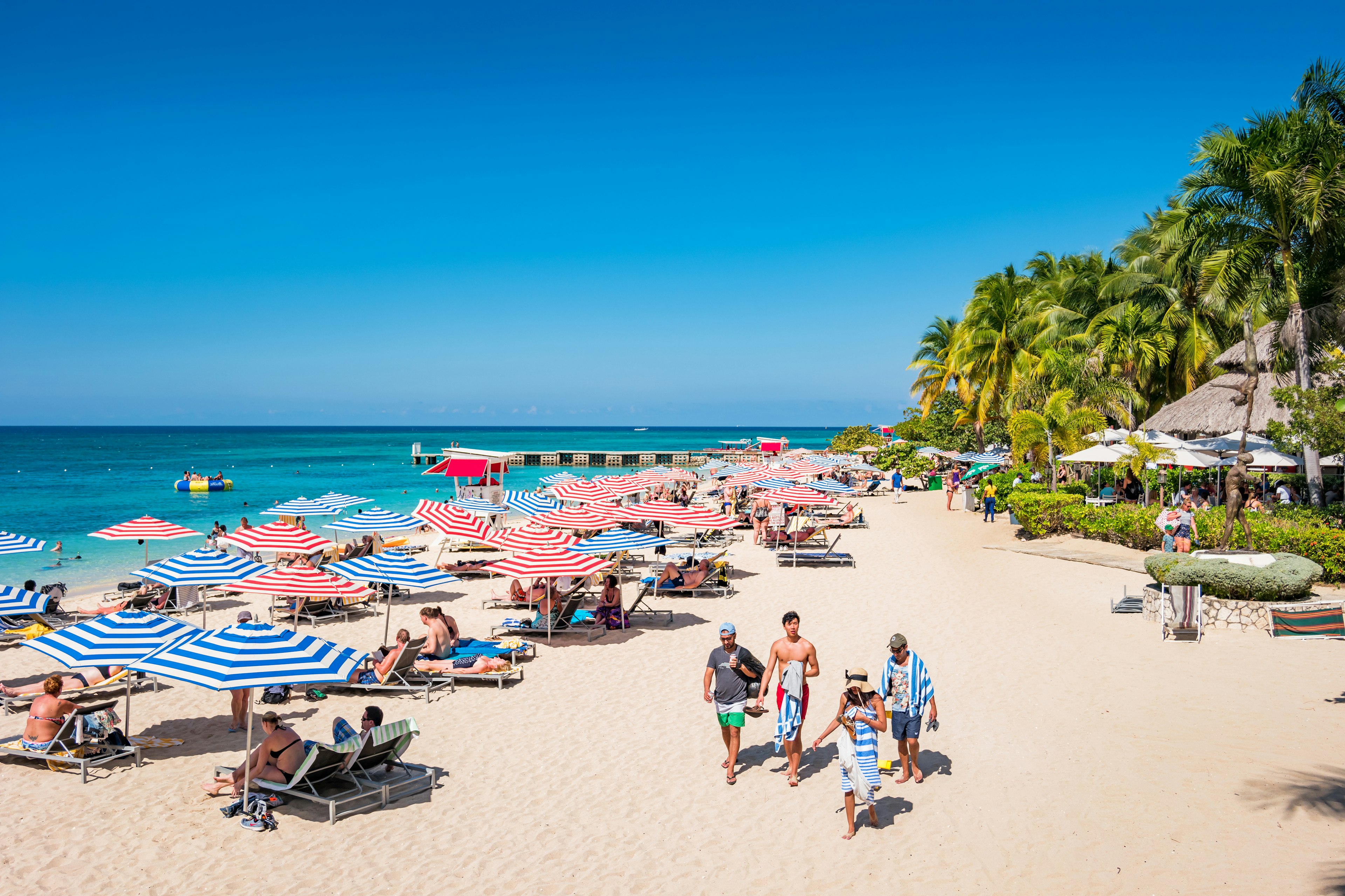 People enjoy Doctor's Cave Beach, a famous, white, sandy beach in Montego Bay Jamaica on a sunny day.