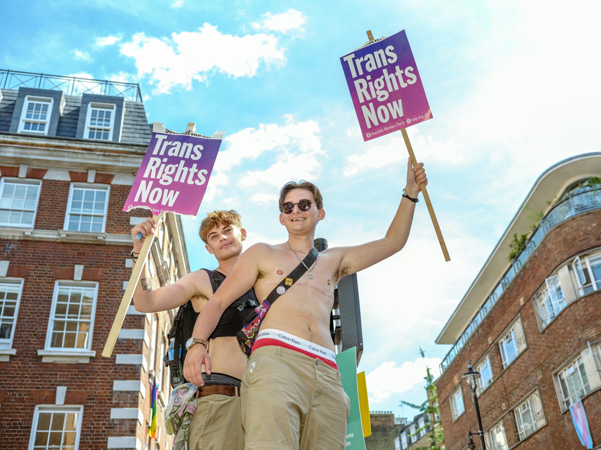 Two people carry signs calling for trans rights during the London Trans Pride march