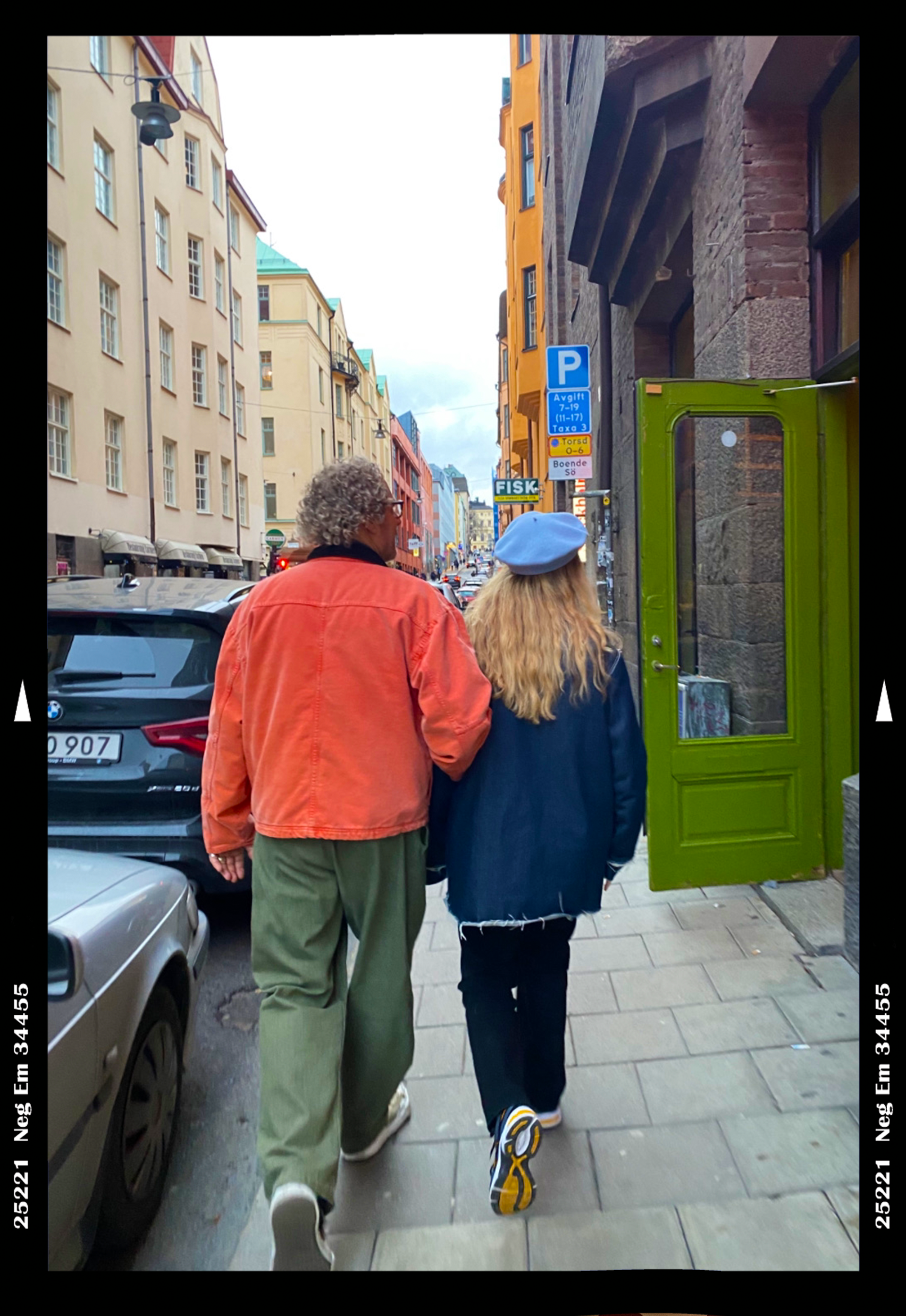 Stylish couple walk arm in arm down a street in Stockholm