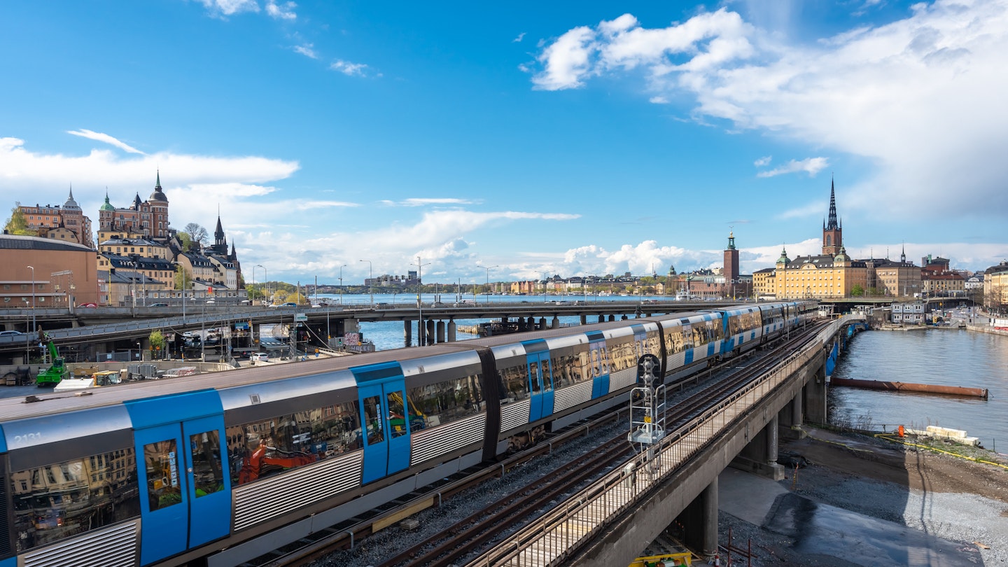 Panoramic view of the center of Stockholm. The metro train moving the Slussen district. Amazing view of the Sodermalm island, The City Hall, Riddarholmen in Gamla Stan. Text on road signs "Old Town"; Shutterstock ID 1722718684; your: Brian Healy; gl: 65