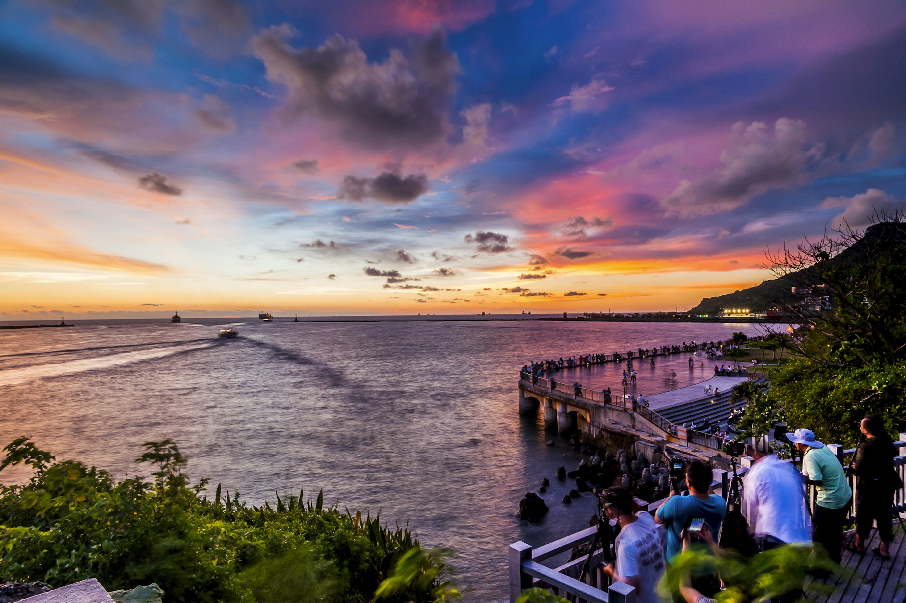 People watch the sunset over the ocean from the harbor in Kaohsiung