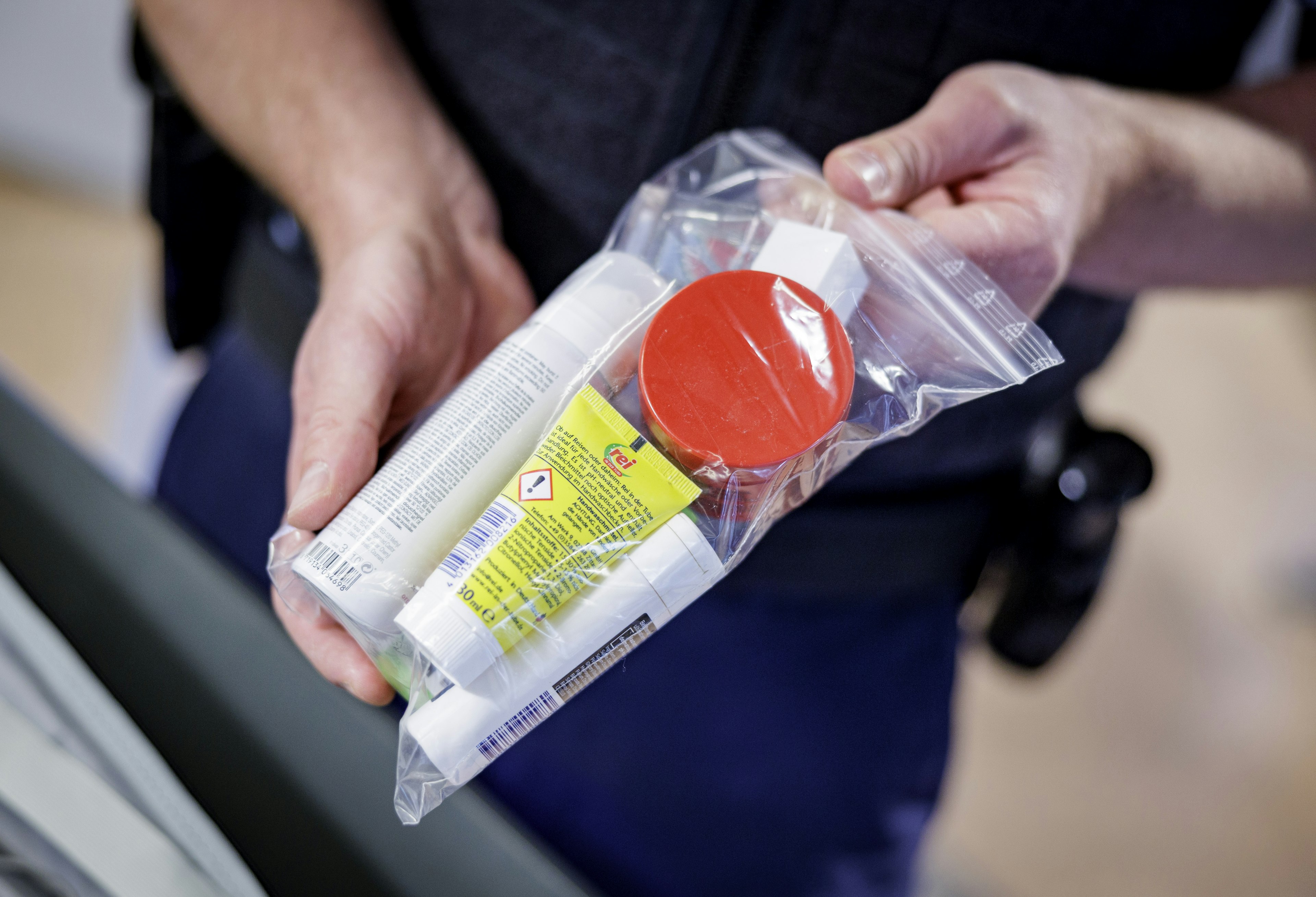 22 June 2022, Hamburg: An officer of the Federal Police shows at Hamburg Airport during the security check which quantities of liquids may be carried and how they must be packed.      (to dpa "Busy at the airport - this is how the security check works") P