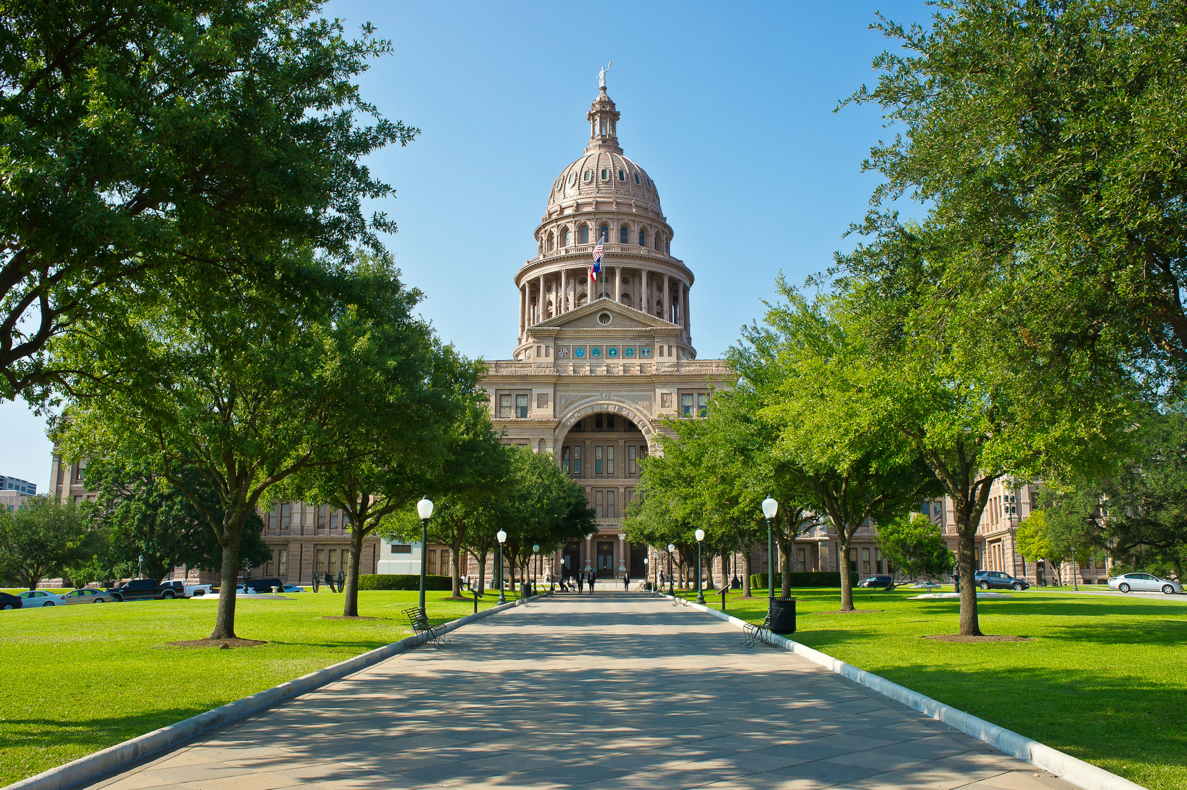 People walk down a path approaching a grand domed government building