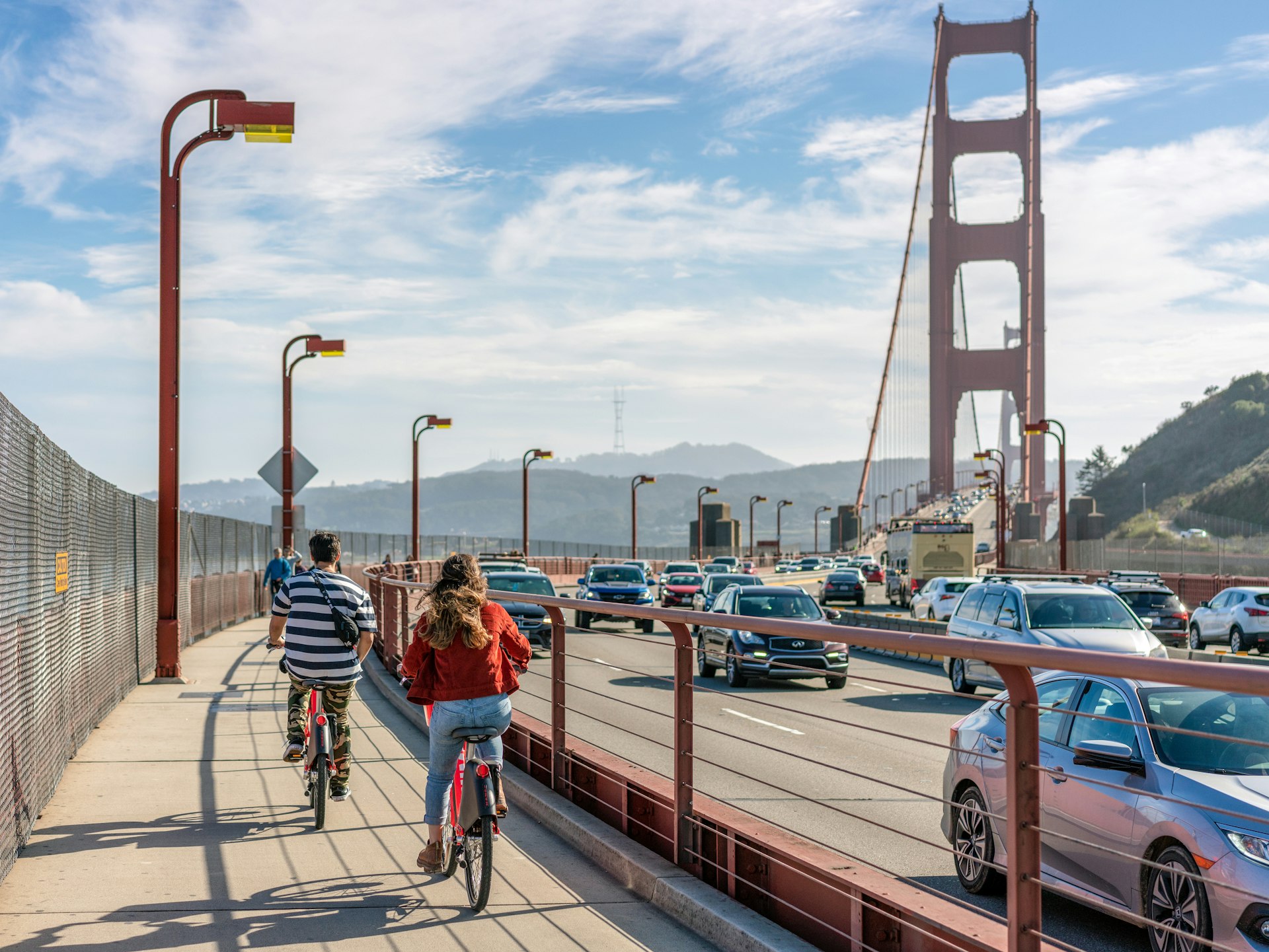 A rear view of people cycling towards the Golden Gate Bridge, heading in the direction of San Francisco.