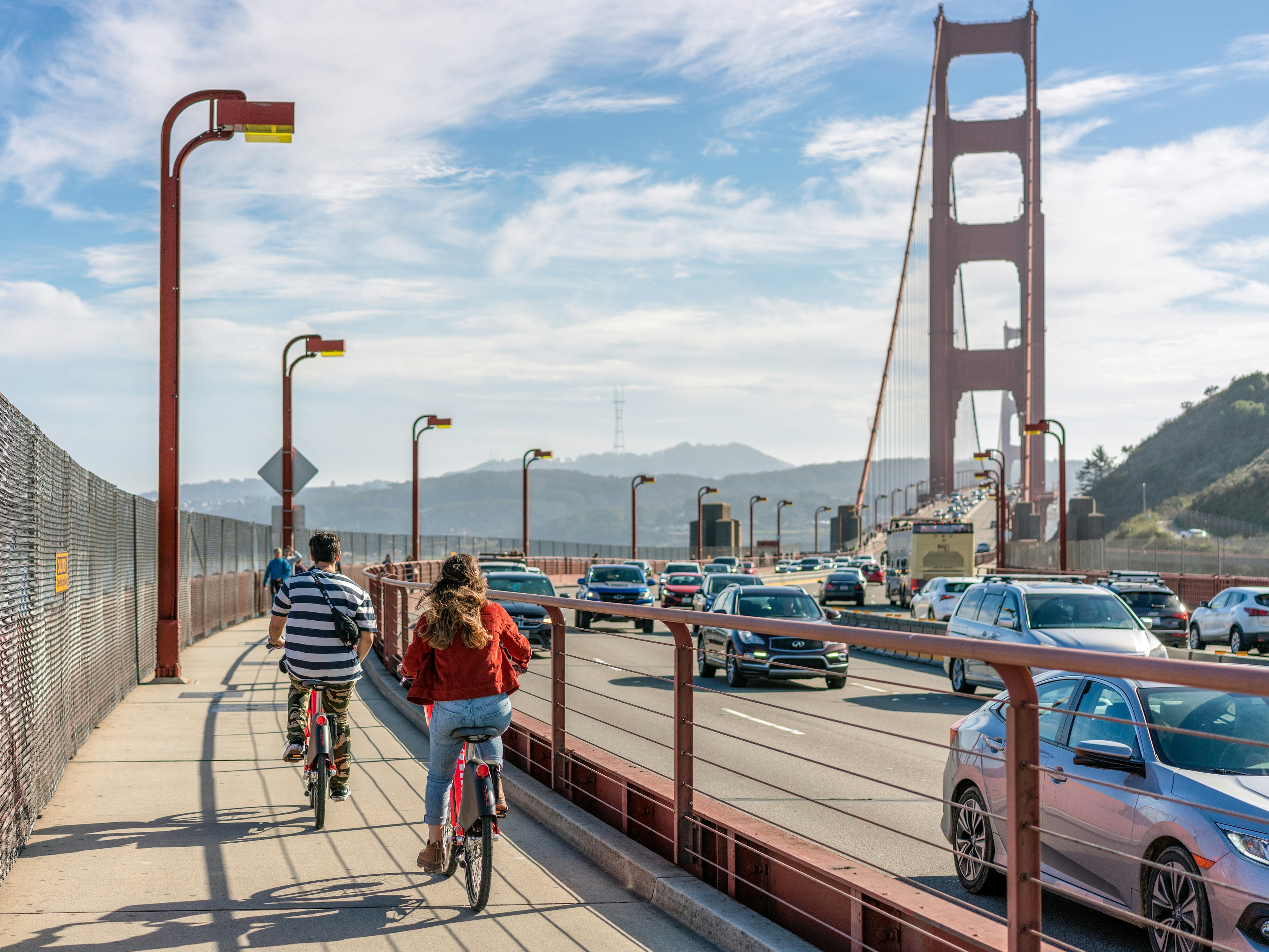 A rear view of people cycling towards the Golden Gate Bridge, heading in the direction of San Francisco.