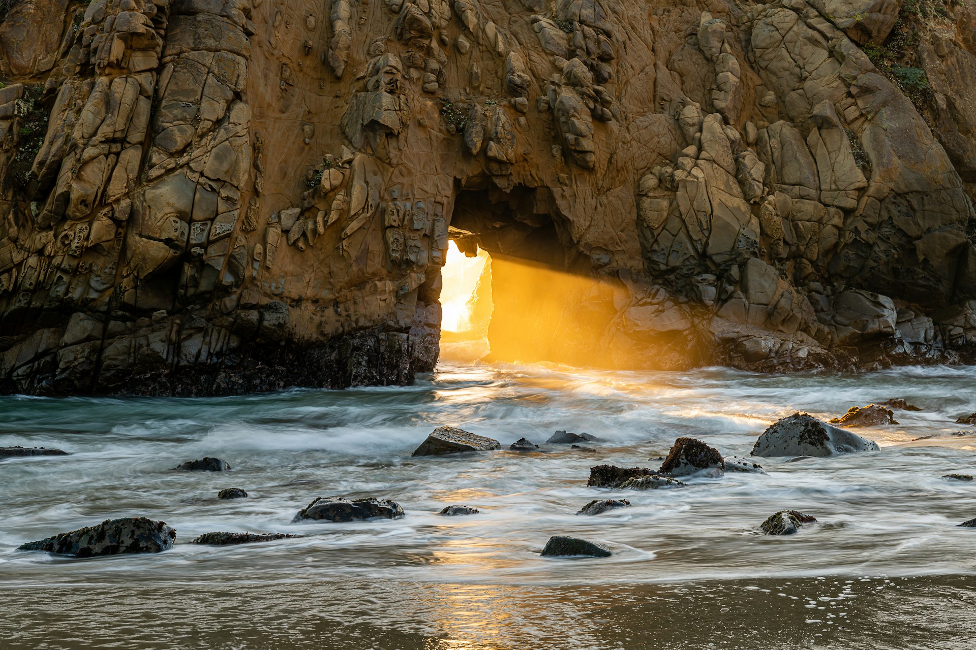 Watching the sun set through Keyhole Arch at Pfeiffer Beach in Big Sur, California.