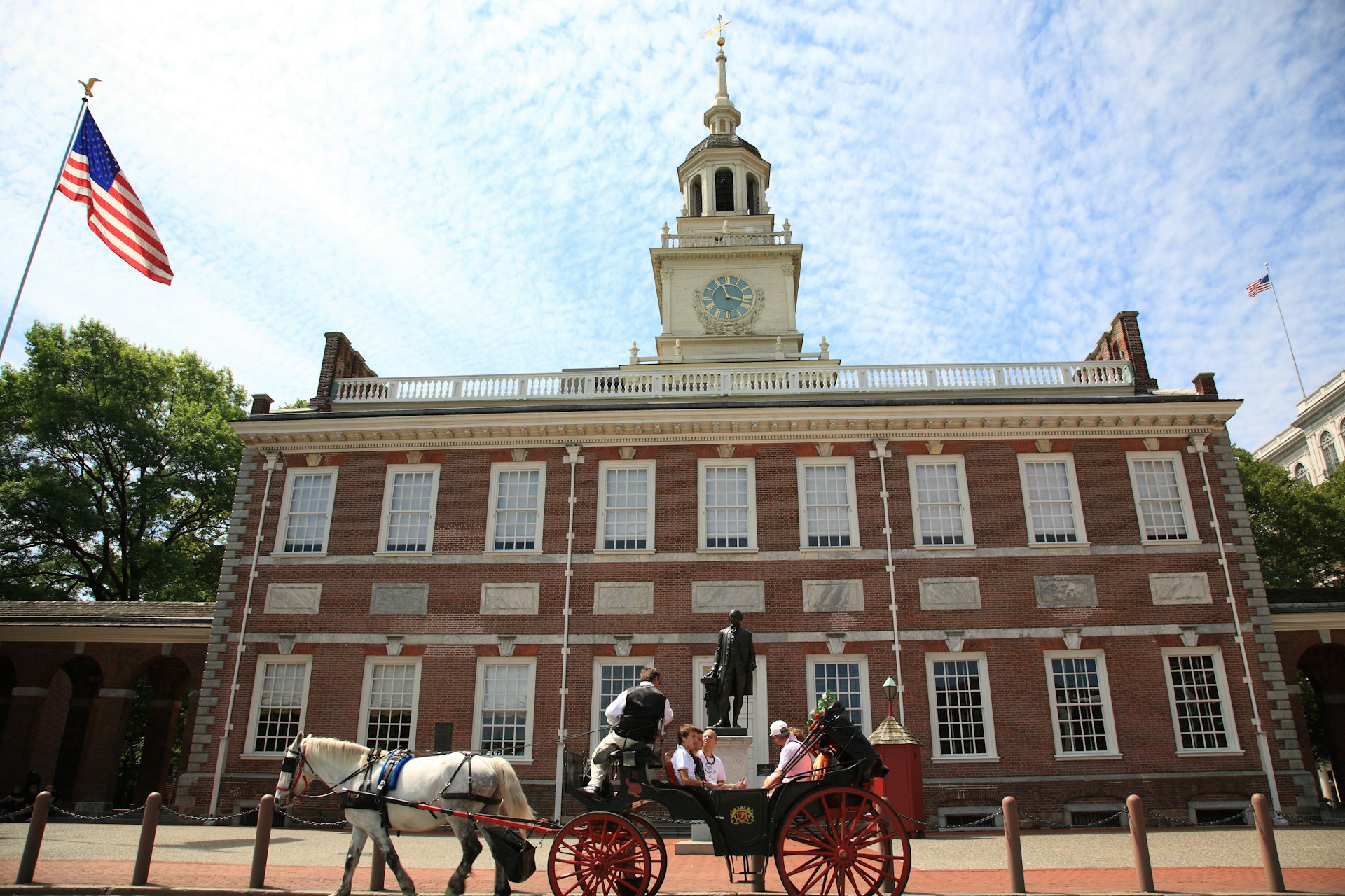 People sit in a horse-drawn carriage outside a historic building
