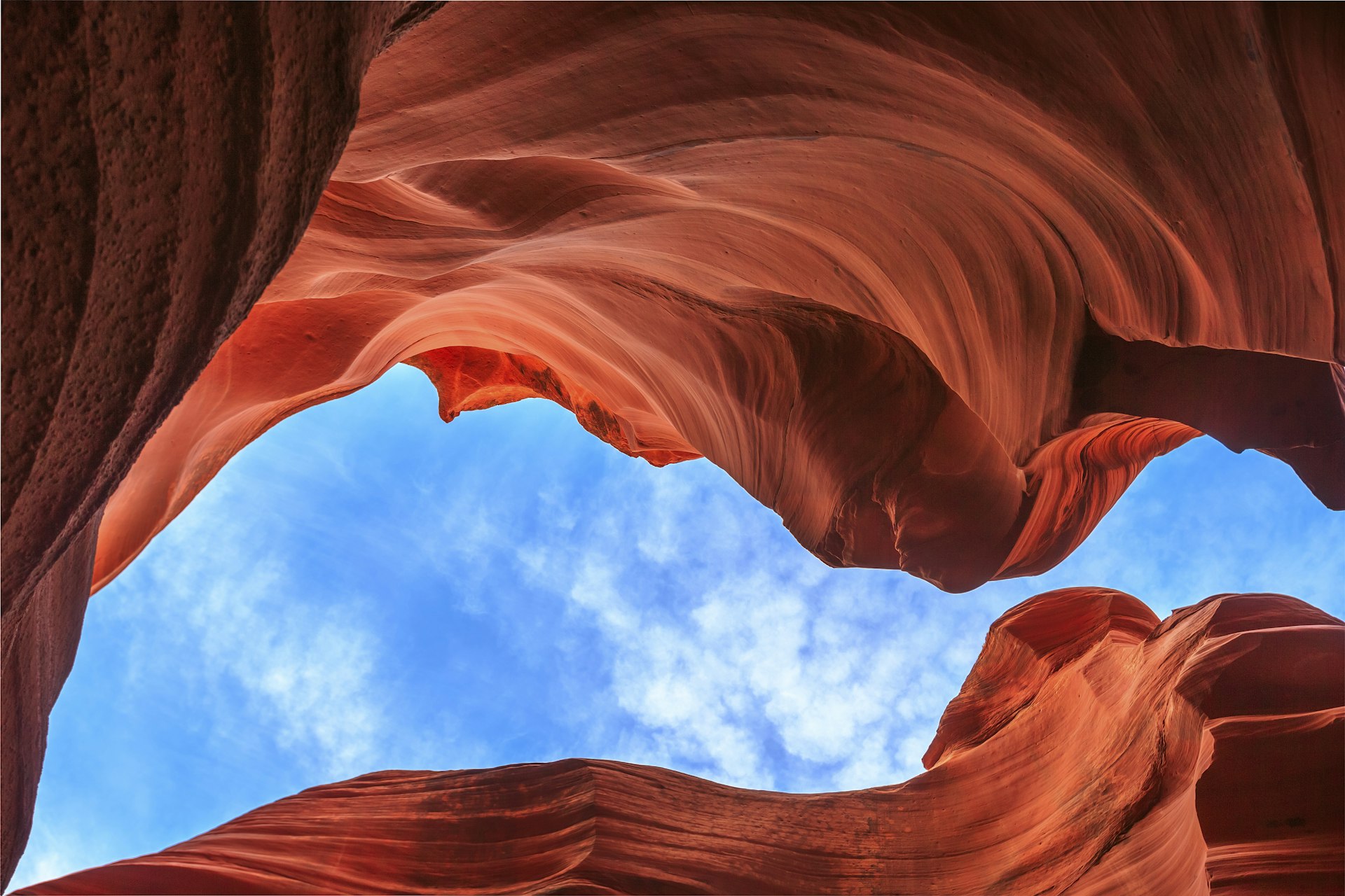 Vibrant red rocks sweep and whirl overhead below a bright blue sky