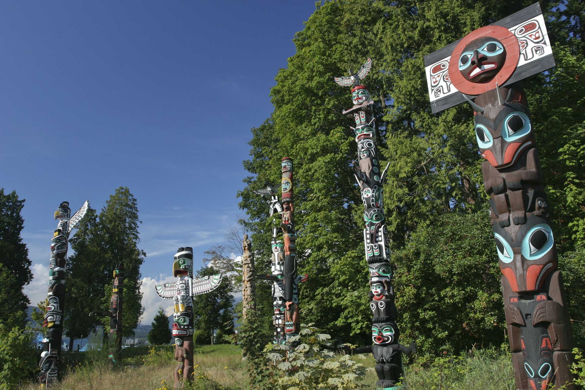 Totem poles in Vancouver, surrounded by trees and greenery 