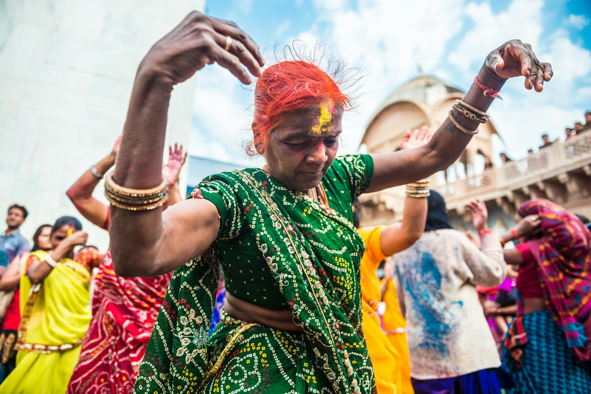 Close-up of a woman in colourful clothes who is dancing in a crowd during the festival of Holi