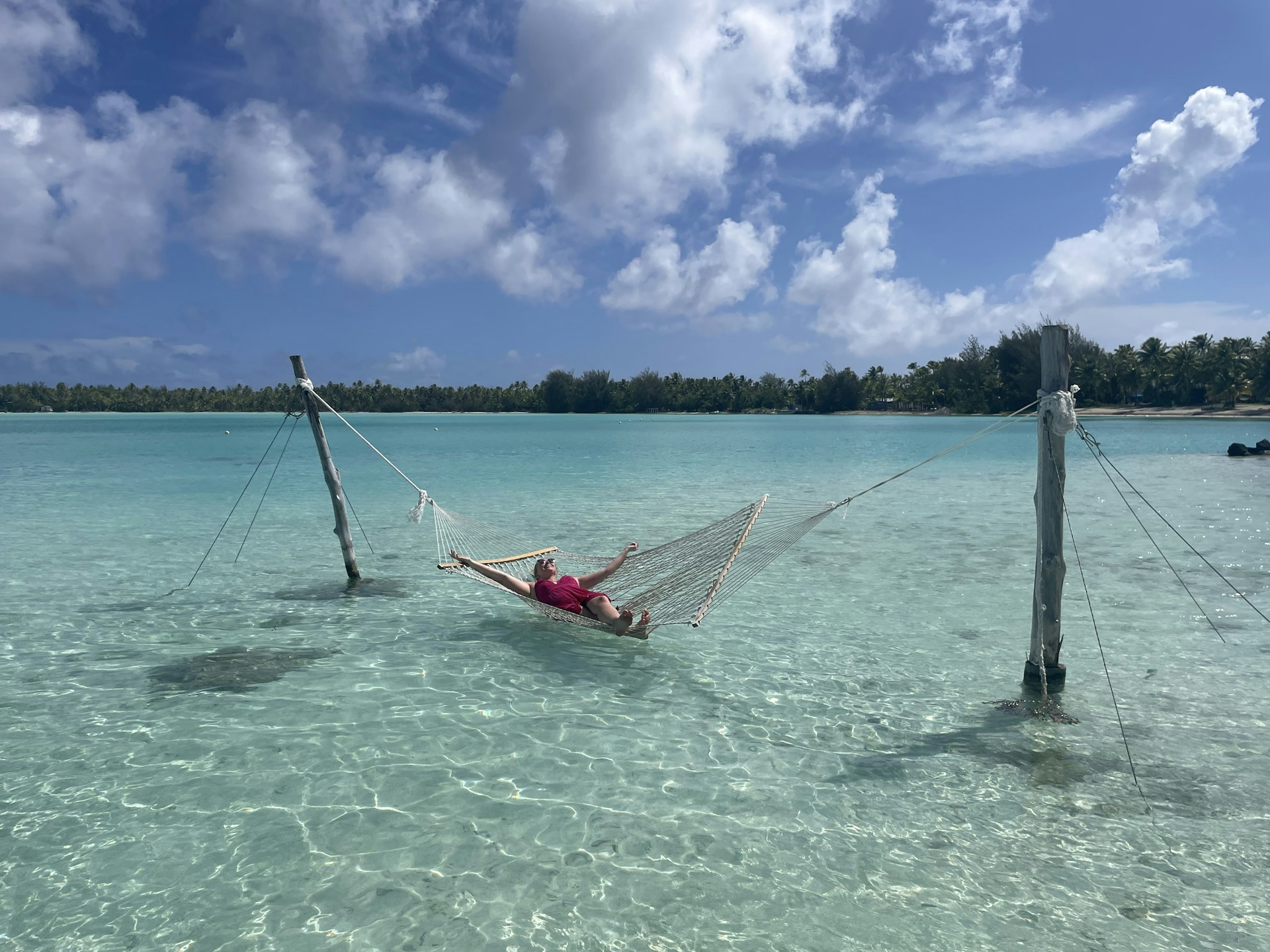 A woman lies on a hammock over blue water in Bora Bora. 