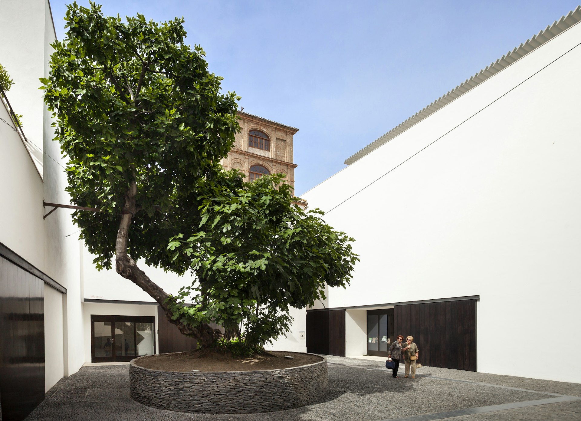 Two women walk through the plaza at the Museo Picasso Malaga. 