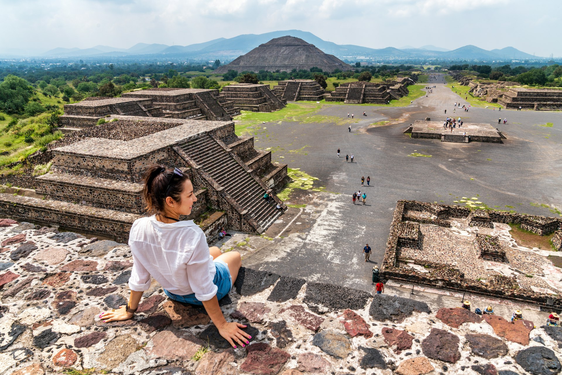 A woman sits on top of a pyramid at the ancient site of Teotihuacán, Mexico