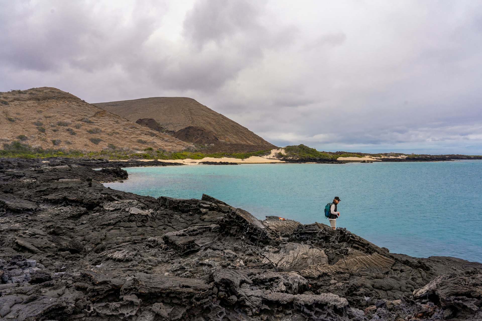 Person standing on a rocky island looking out at the water in the Galapagos Islands