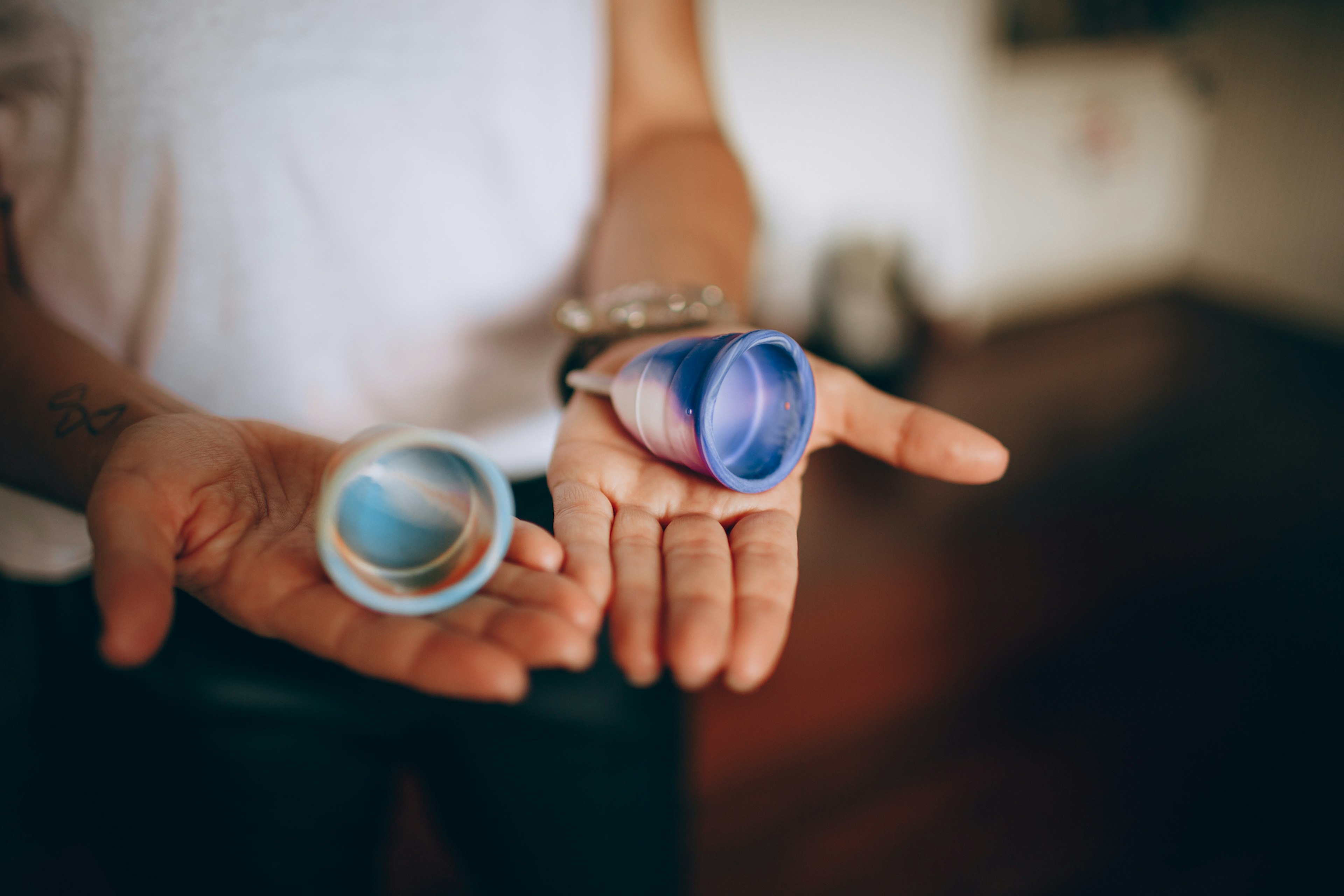 A woman holds two silicone menstrual cups in the palms of her two hands, Brazil